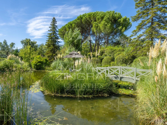 Jardin paysager avec étang et pont en bois dans une villa provençale à Châteauneuf-Grasse.
