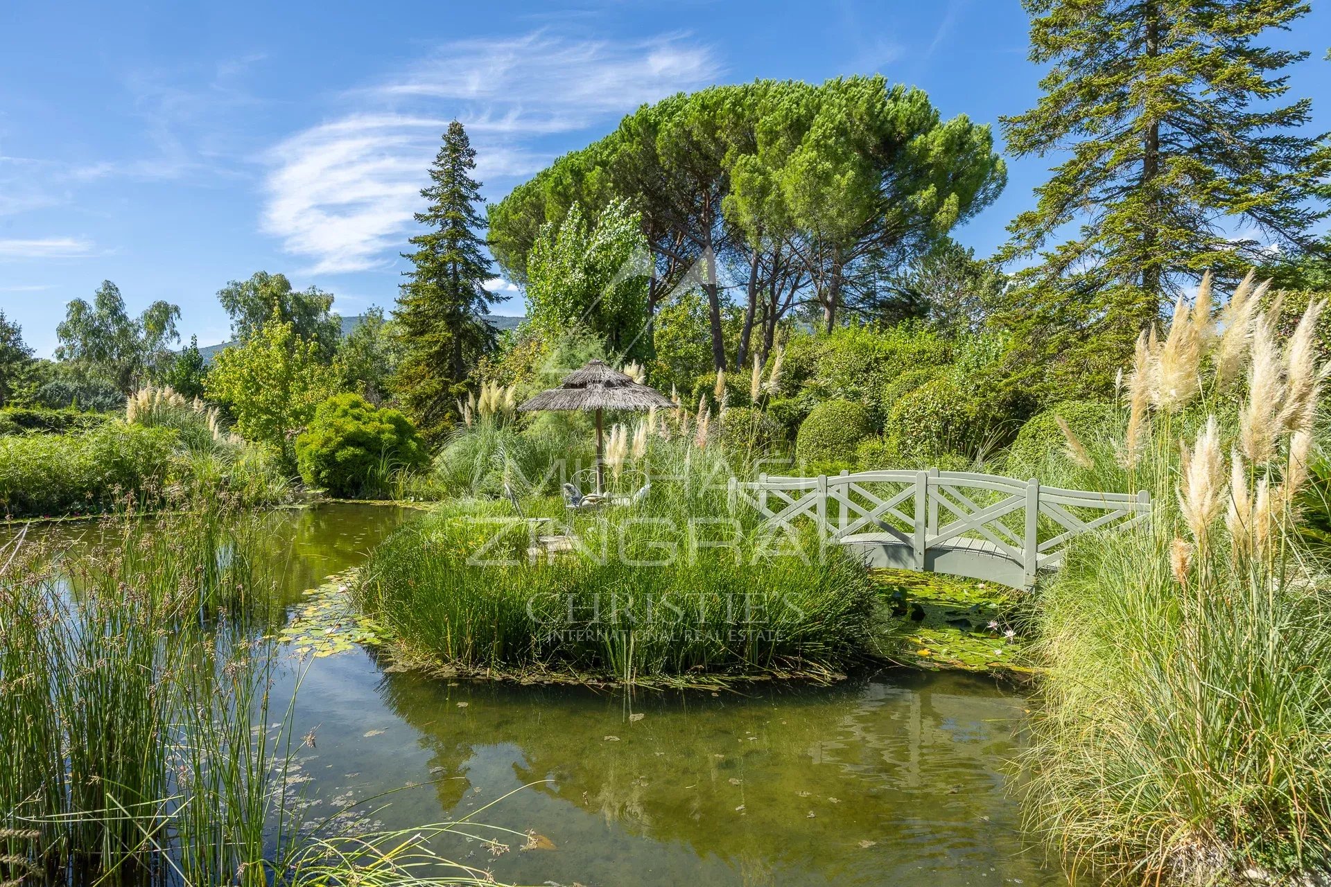 Jardin de villa provençale Jardin paysager avec étang et pont en bois dans une villa provençale à Châteauneuf-Grasse.