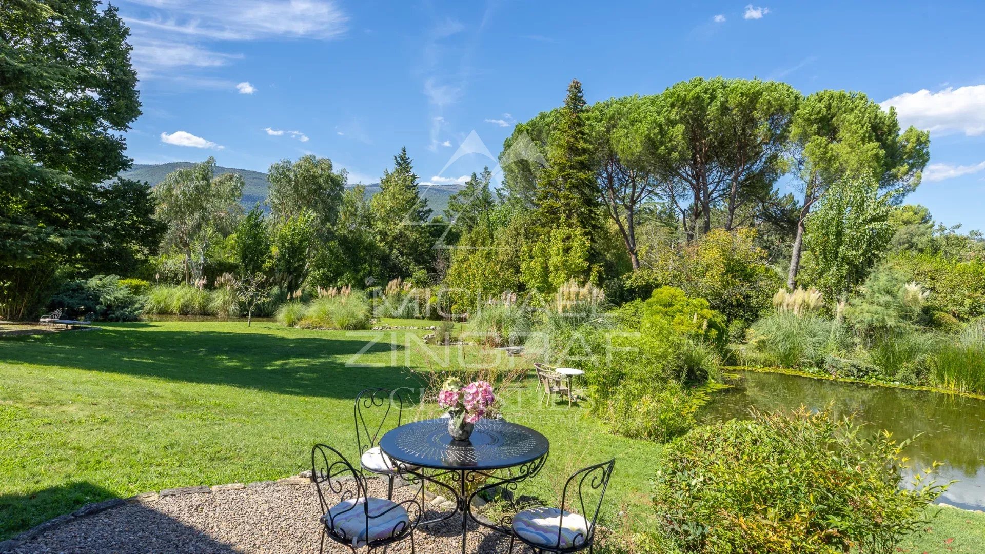 Jardin d’une villa provençale Vue d'un jardin paysager avec étang et mobilier de jardin, Châteauneuf-Grasse.