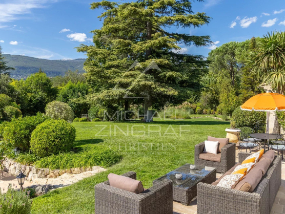 Jardin paysager avec mobilier extérieur et parasol dans une villa provençale à Châteauneuf-Grasse.