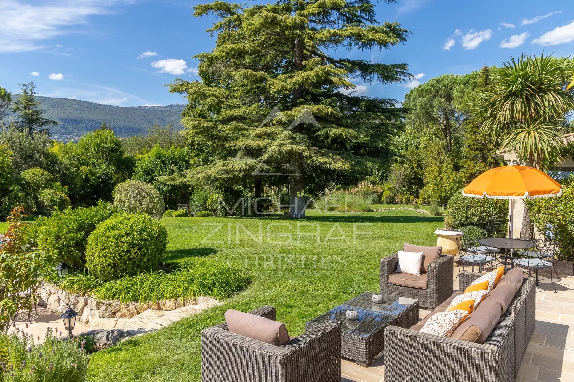 Jardin d’une villa provençale Jardin paysager avec mobilier extérieur et parasol dans une villa provençale à Châteauneuf-Grasse.