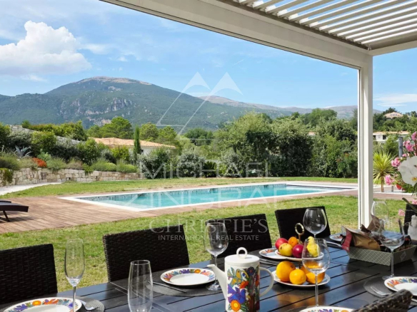 Terrasse d'une villa contemporaine avec vue sur les collines, piscine et table dressée.
