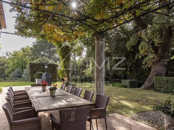 Terrasse d'une bastide aixoise avec table et chaises, entourée de verdure dans un parc paysager.