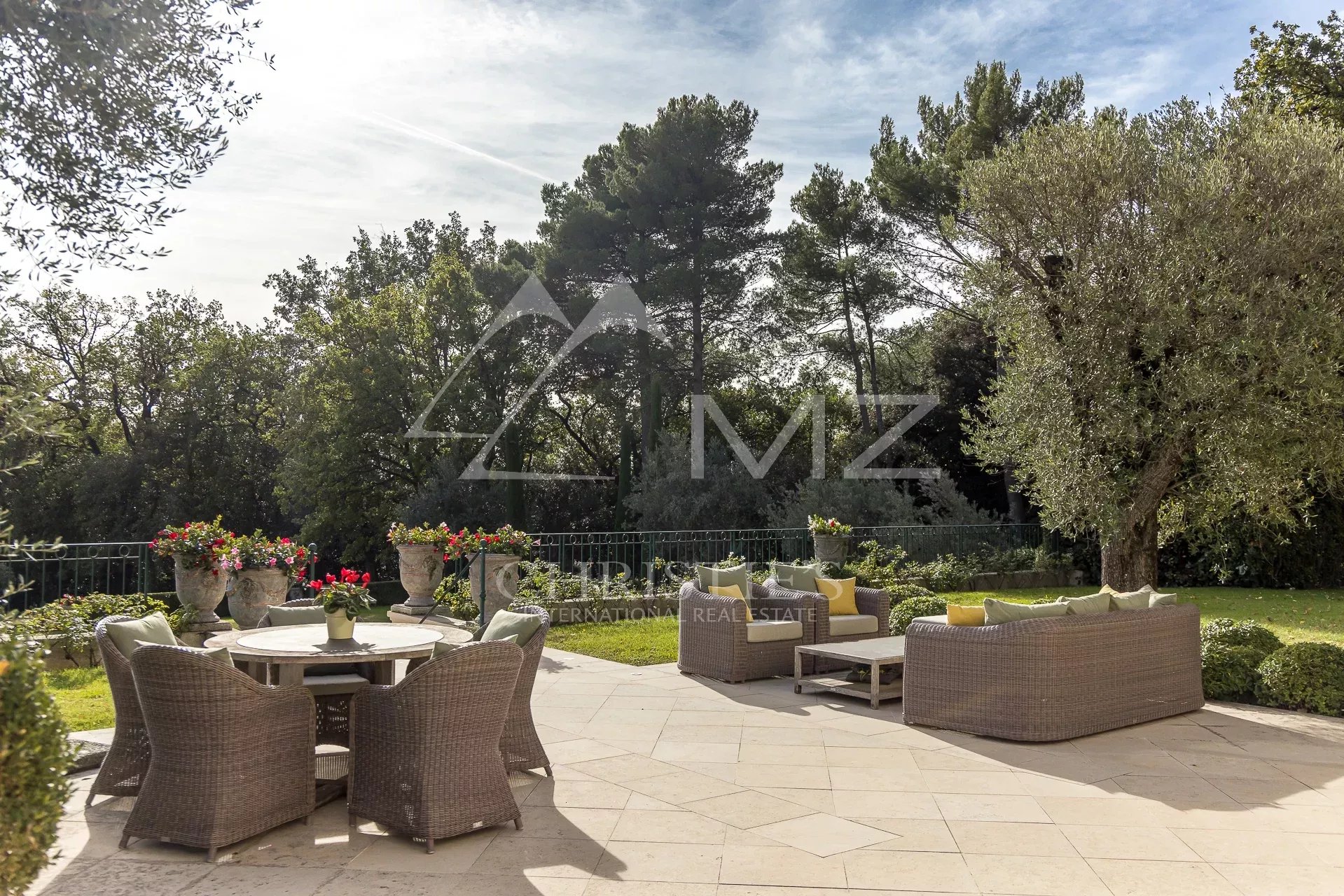 Terrasse de la Bastide Aixoise Terrasse d'une bastide aixoise avec mobilier en osier et vue sur un parc arboré.