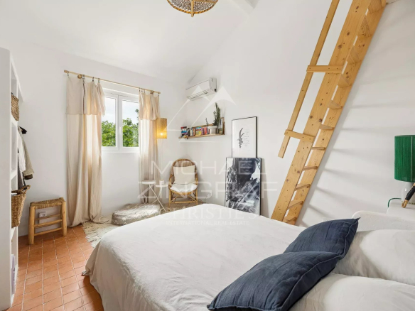 Bright room with double bed, wooden ladder and Mediterranean decor.
