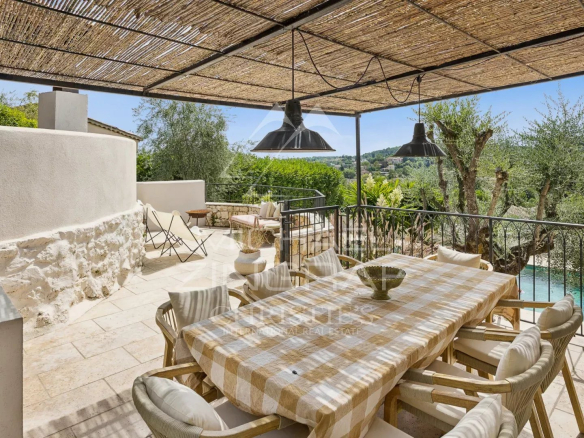 Terrace of a villa in Le Rouret with views of the hills, wooden furniture and dining table.