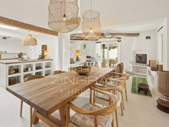 Interior of a Mediterranean villa with a large wooden table and wicker light fixtures.