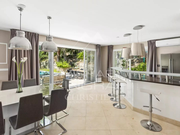 Intérieur d'une villa à Grasse avec cuisine moderne et salle à manger, vue sur la piscine extérieure.