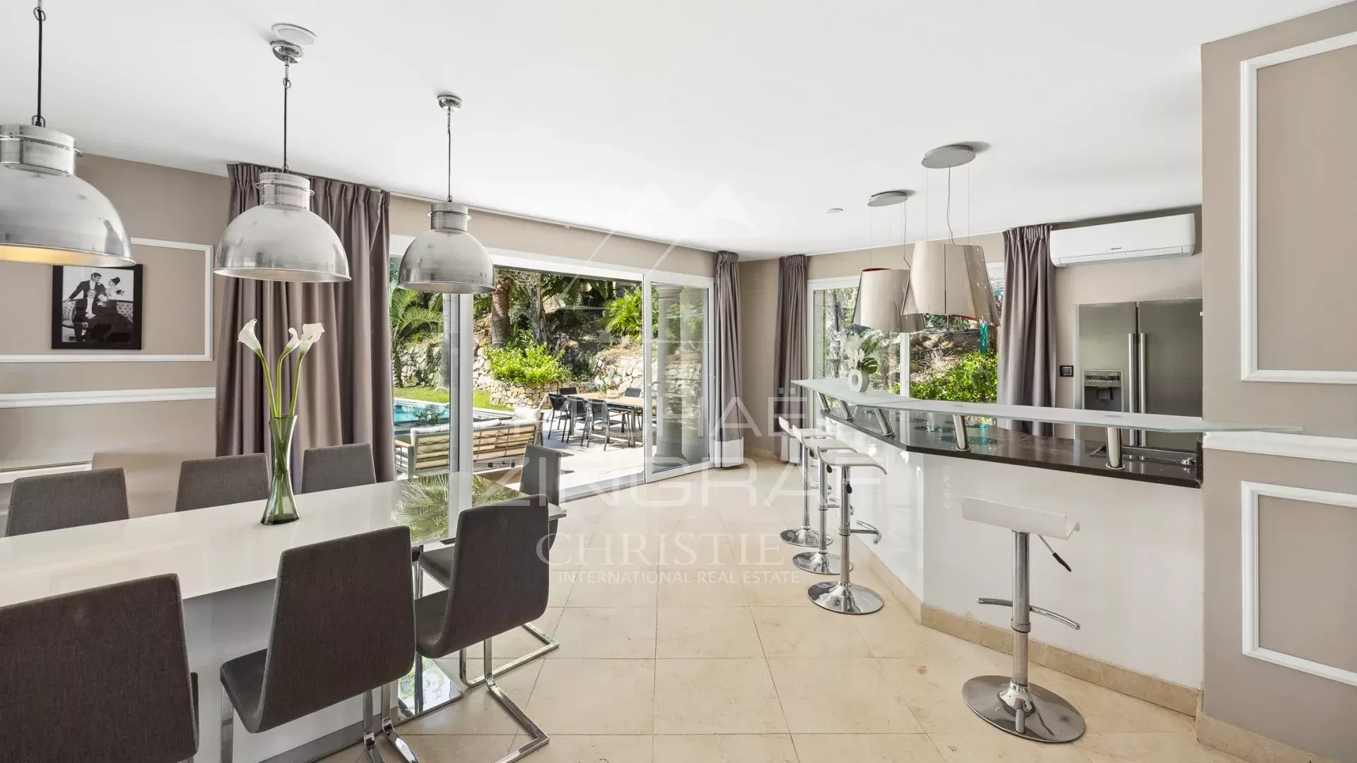 Intérieur d'une villa à Grasse avec cuisine moderne et salle à manger, vue sur la piscine extérieure.