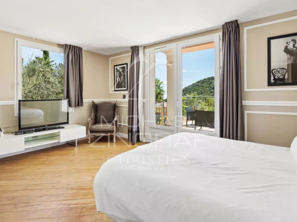 Chambre lumineuse avec vue sur les collines, mobilier moderne et accès à un balcon.
