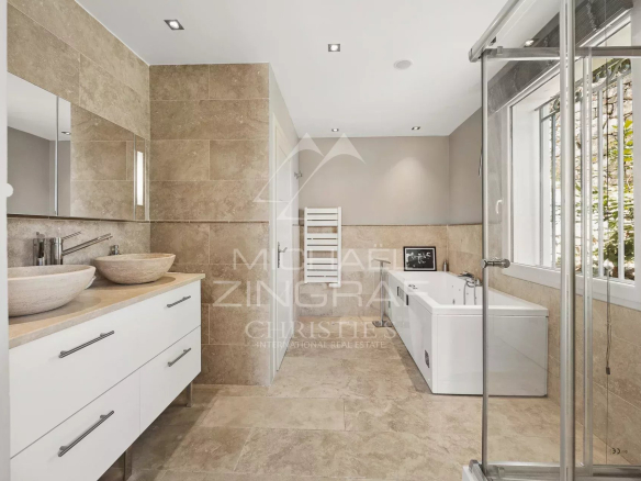 Salle de bains moderne avec baignoire et douche, décorée en pierre beige.