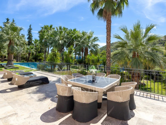 Terrasse d'une bastide contemporaine avec vue sur des palmiers et une piscine à Grasse.