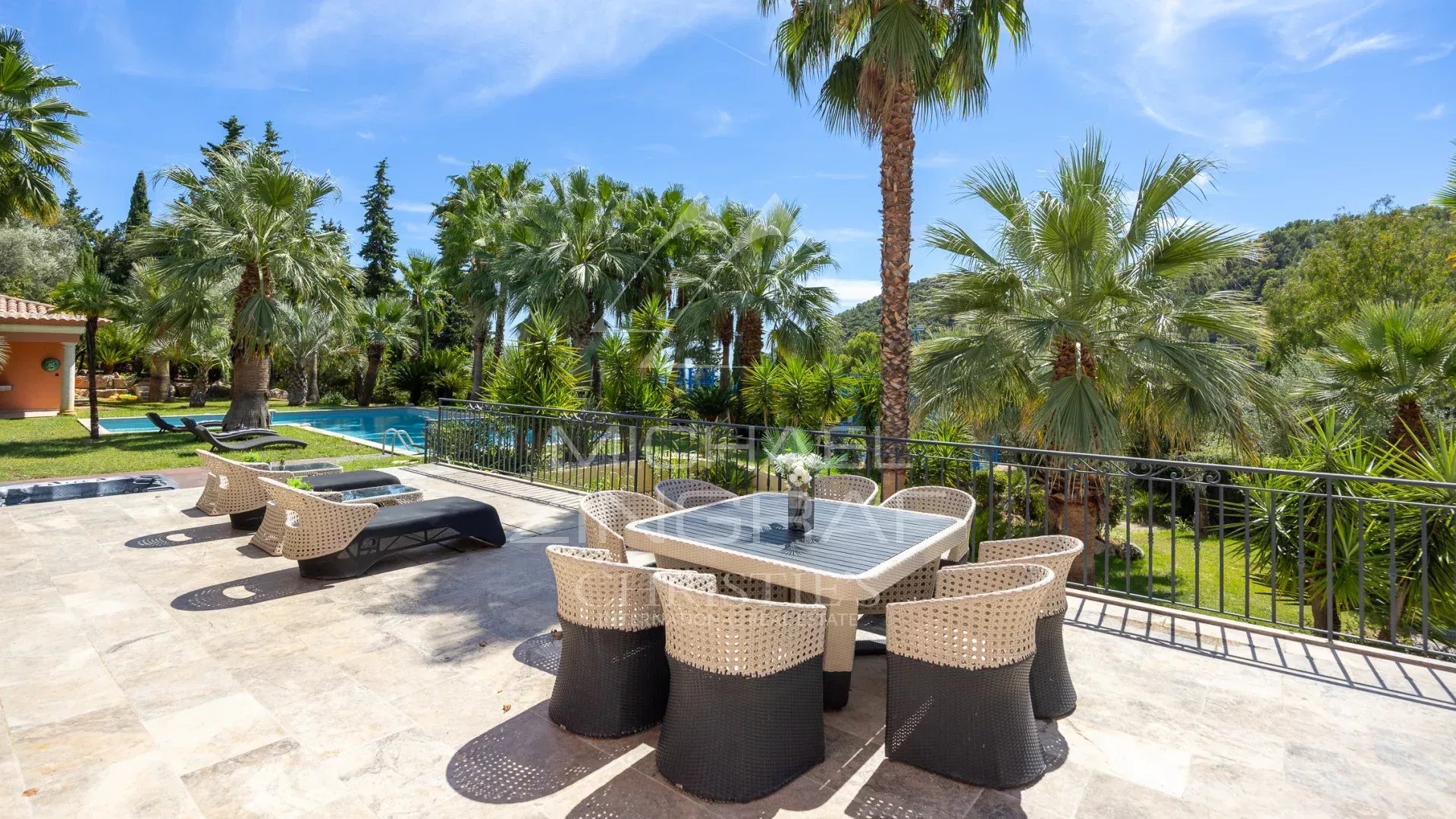Terrasse d'une bastide contemporaine avec vue sur des palmiers et une piscine à Grasse.