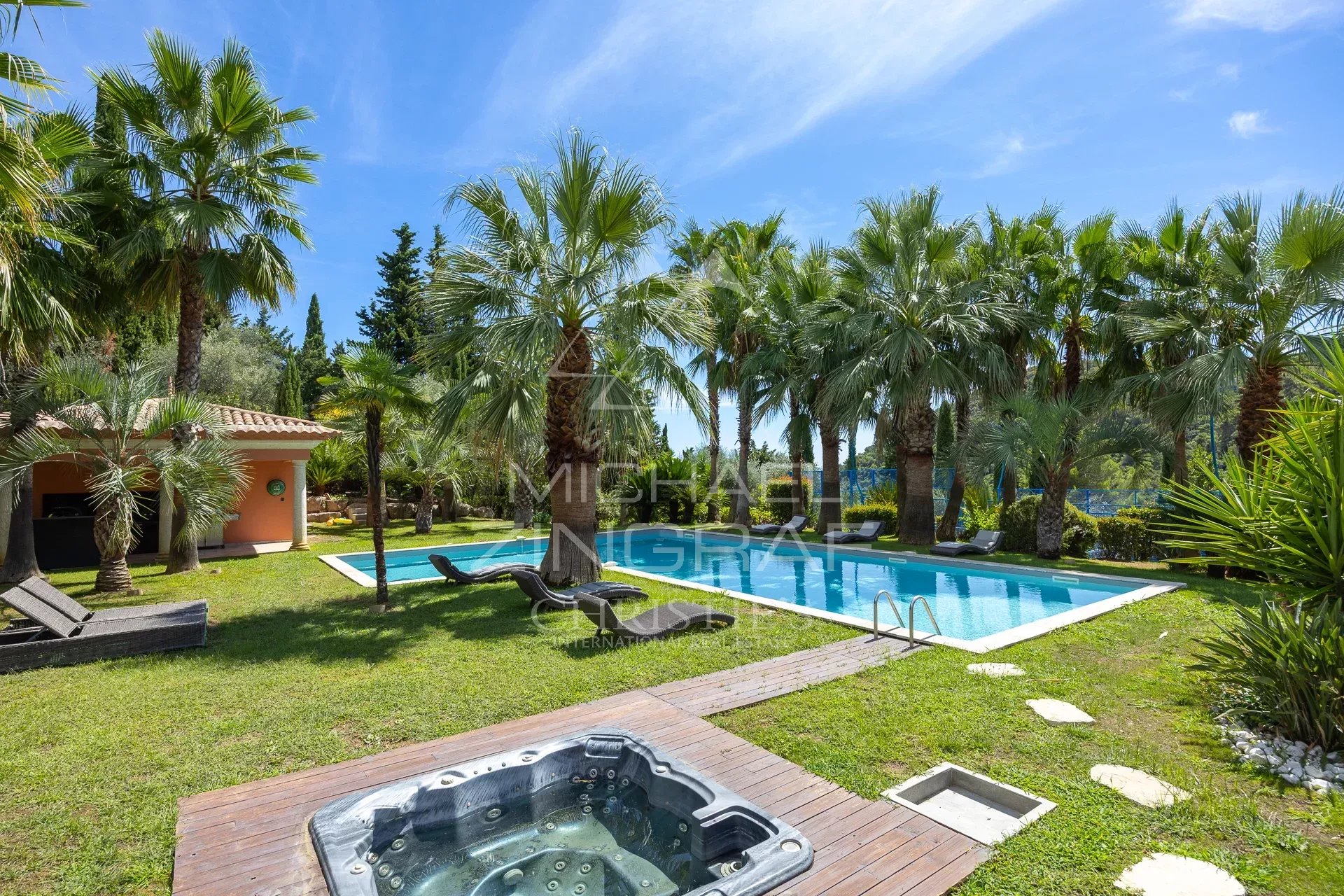 Bastide contemporaine avec piscine et jardin à Grasse, entourée de palmiers.