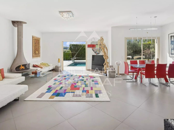 Intérieur d'une villa moderne avec salon et salle à manger, piscine visible à l'extérieur.