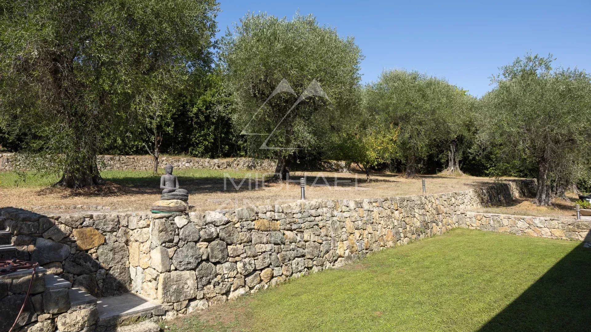 Jardin d'une villa avec oliveraie et mur en pierre à Grasse
