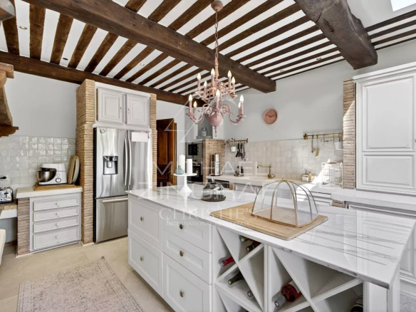 Modern kitchen with exposed beams and central island in a renovated property in Le Bar-sur-Loup.