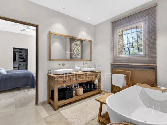 Modern bathroom with wooden bathtub and sink in a renovated property.