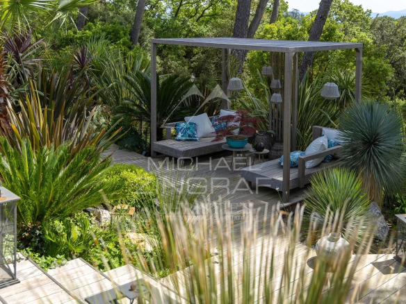 Outdoor space of a charming estate in Draguignan, with plants and a wooden seating area.