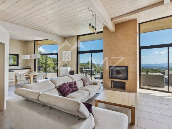 Interior of a modern villa with a spacious living room, open kitchen and terrace offering panoramic views.