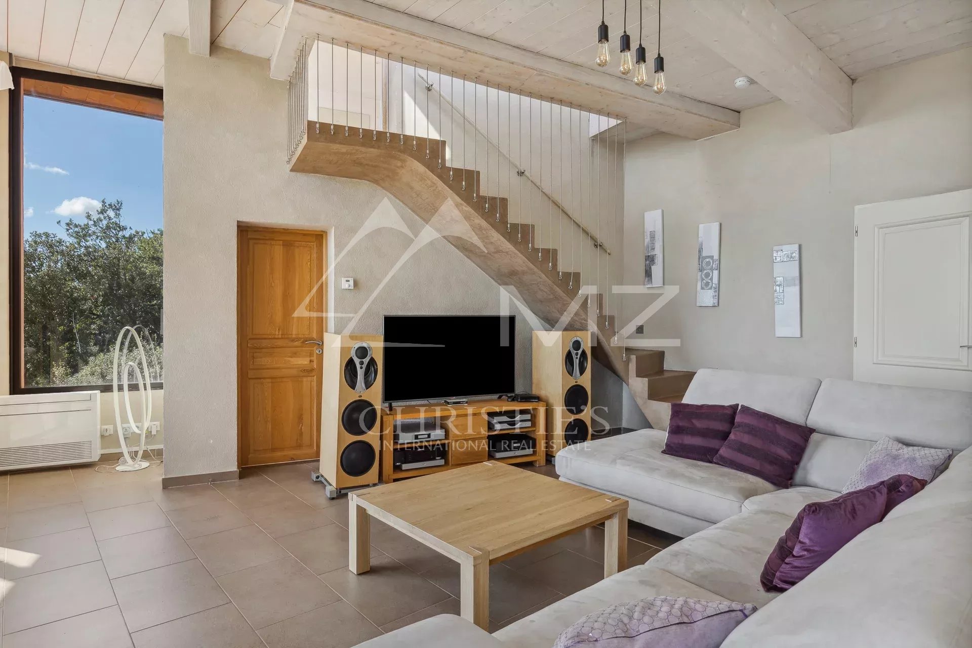 Interior of a villa in Fayence with a bright living room and wooden staircase.