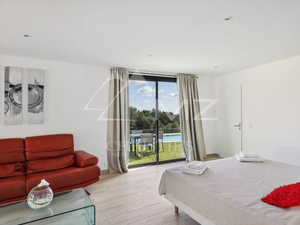 Bright room with pool view, red sofa and light bedding.