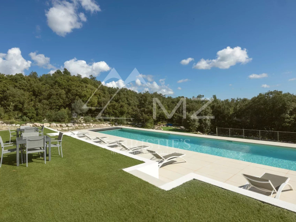 Swimming pool and terrace in an estate in Fayence, with sun loungers and surrounding greenery.
