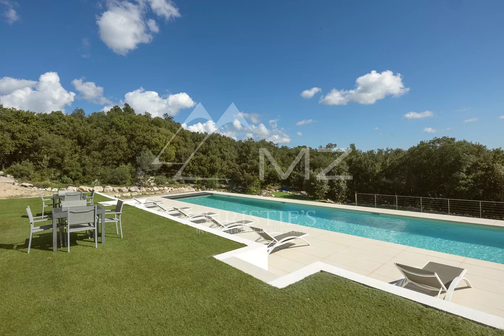 Swimming pool and terrace in an estate in Fayence, with sun loungers and surrounding greenery.
