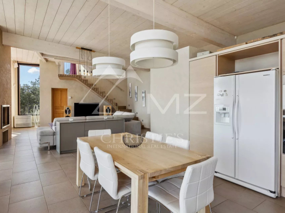 Interior of a modern property with open kitchen and dining room, overlooking the landscape.