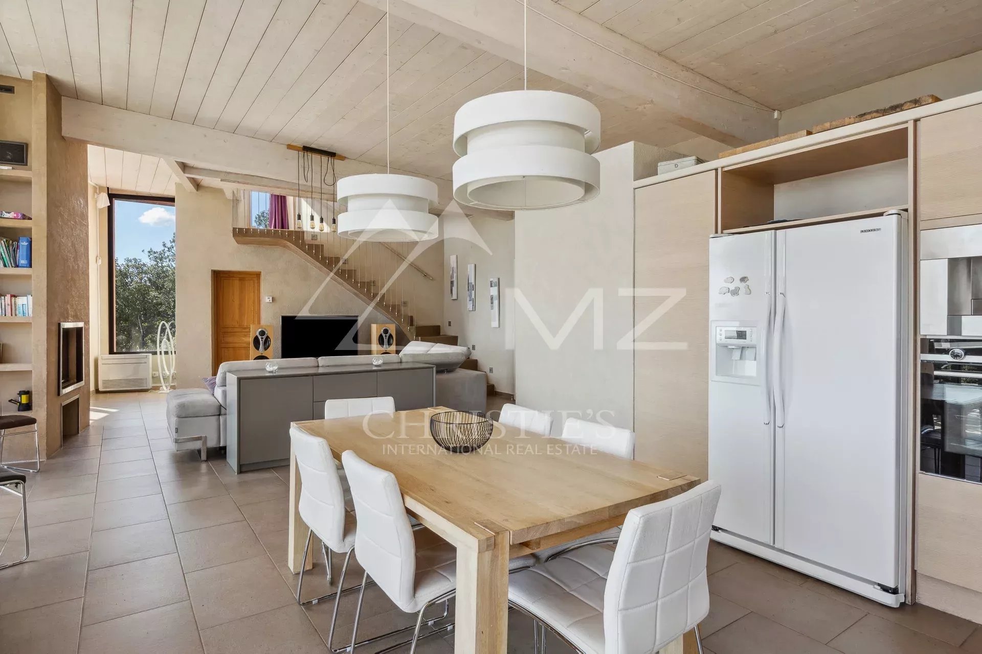 Interior of a modern property with open kitchen and dining room, overlooking the landscape.