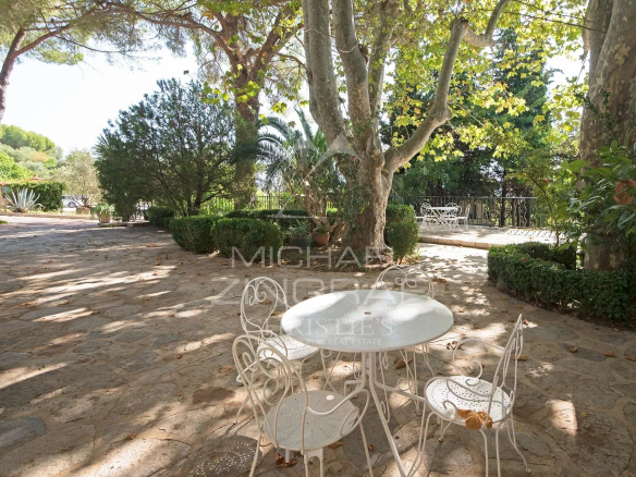 Terrasse avec table et chaises en fer forgé sous des arbres, dans un domaine de figuiers à Solliès-Pont.