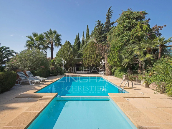 Piscine entourée de palmiers et de verdure dans une bastide provençale à Solliès-Pont.