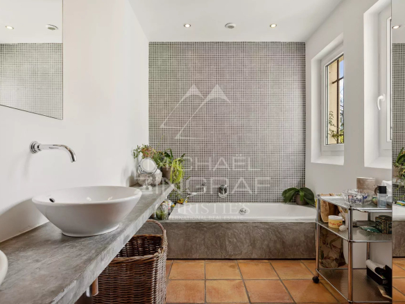 Salle de bain moderne avec baignoire et lavabo, décorée de carrelage et plantes