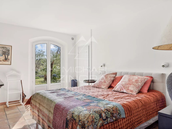Chambre d'une bastide avec lit double et vue sur le parc arboré à Grasse.