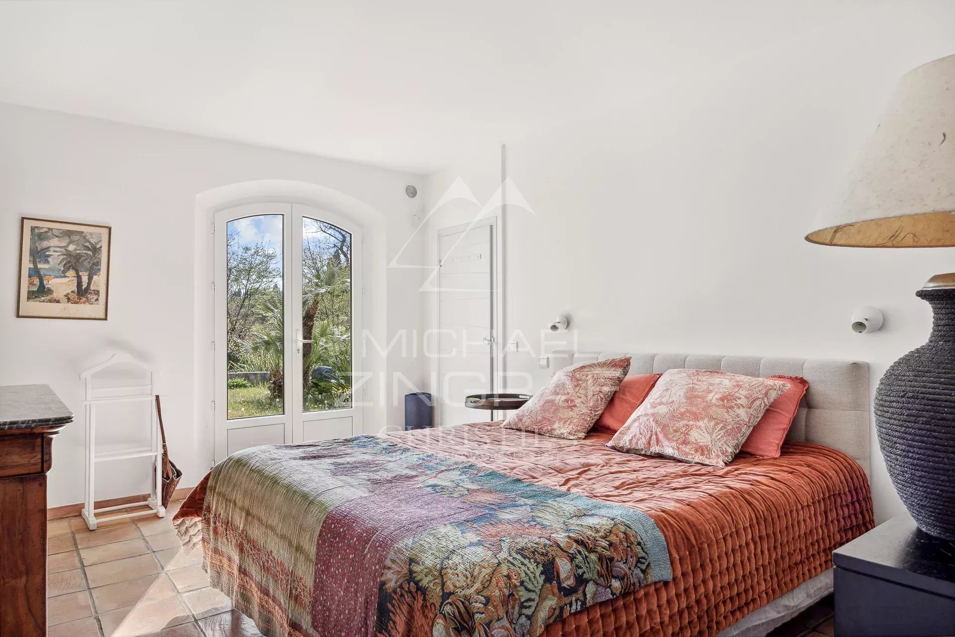 Chambre d’une bastide à Grasse Chambre d'une bastide avec lit double et vue sur le parc arboré à Grasse.