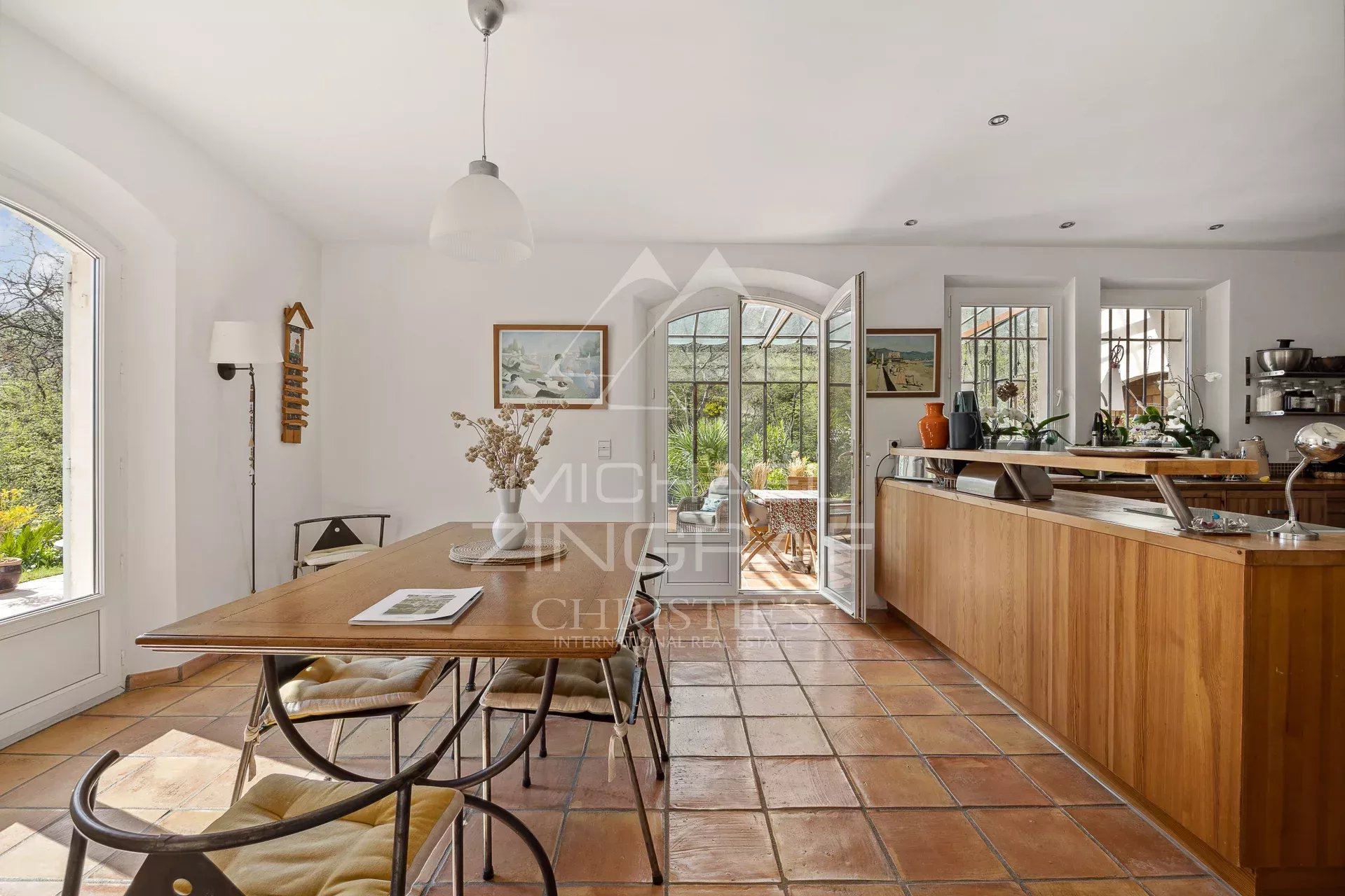 Intérieur d’une bastide à Grasse Intérieur d'une bastide avec table en bois et baies vitrées donnant sur le jardin.