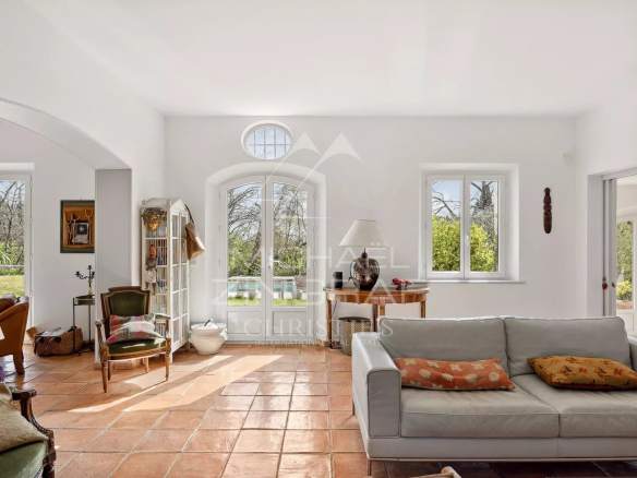 Intérieur lumineux d'une bastide moderne avec salon et grandes fenêtres donnant sur le parc.