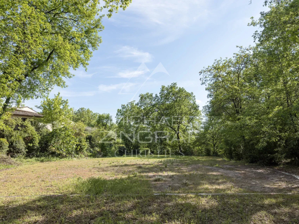 Vaste parc arboré autour d'une bastide à Grasse, avec arbres et ciel dégagé.