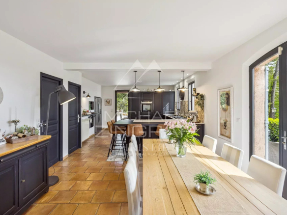 Interior of an elegant country house with a large wooden table and an open kitchen.