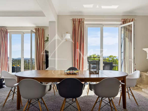 Interior of a villa in Châteauneuf-Grasse with a large dining table and windows opening onto the view.