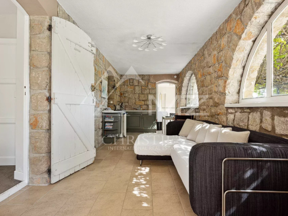 Interior of a villa with stone walls and sofa, overlooking a kitchen.