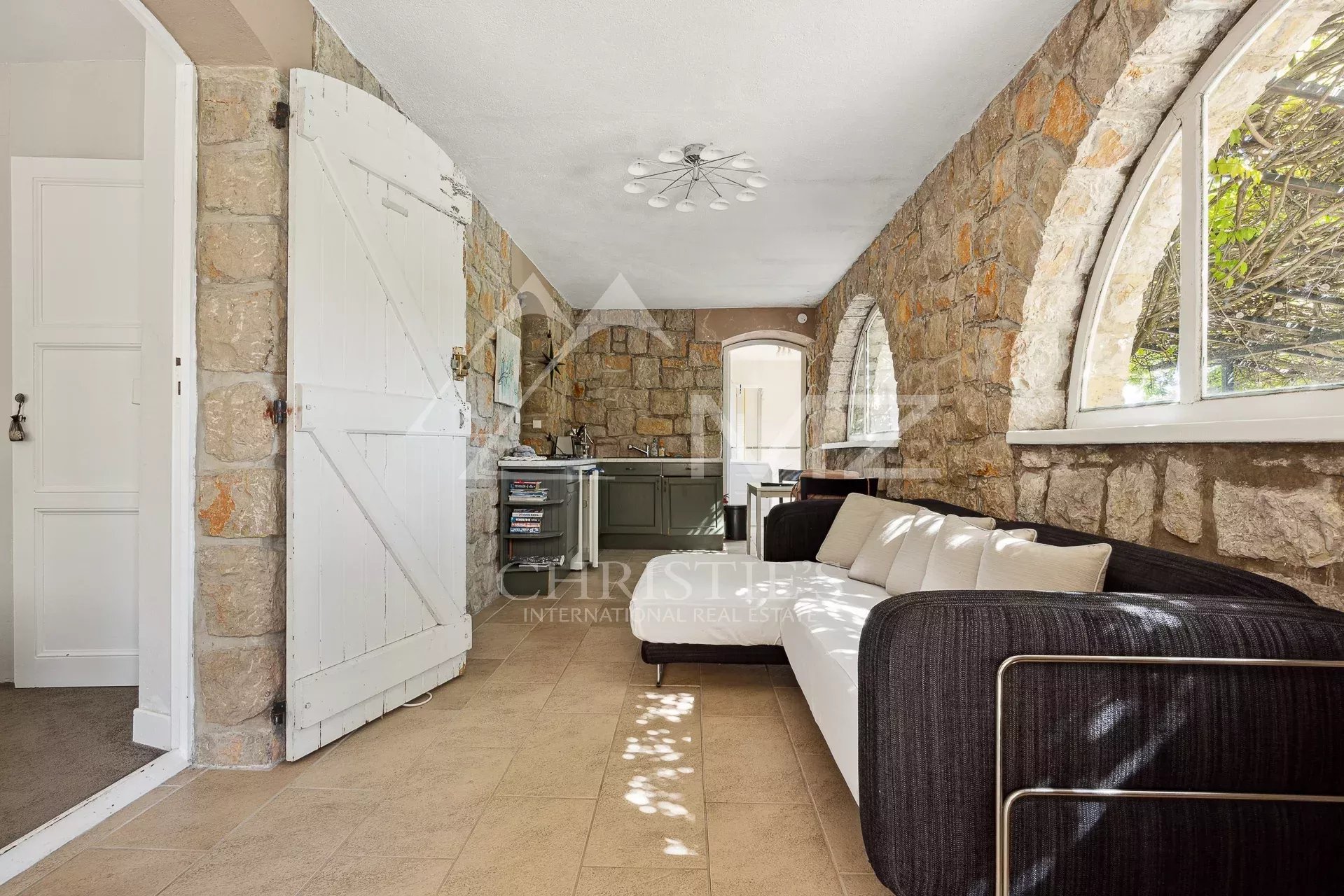 Interior of a villa in Châteauneuf-Grasse Interior of a villa with stone walls and sofa, overlooking a kitchen.