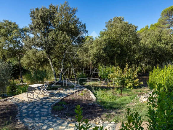 Jardin d'une propriété en Provence avec des arbres et une table en pierre.