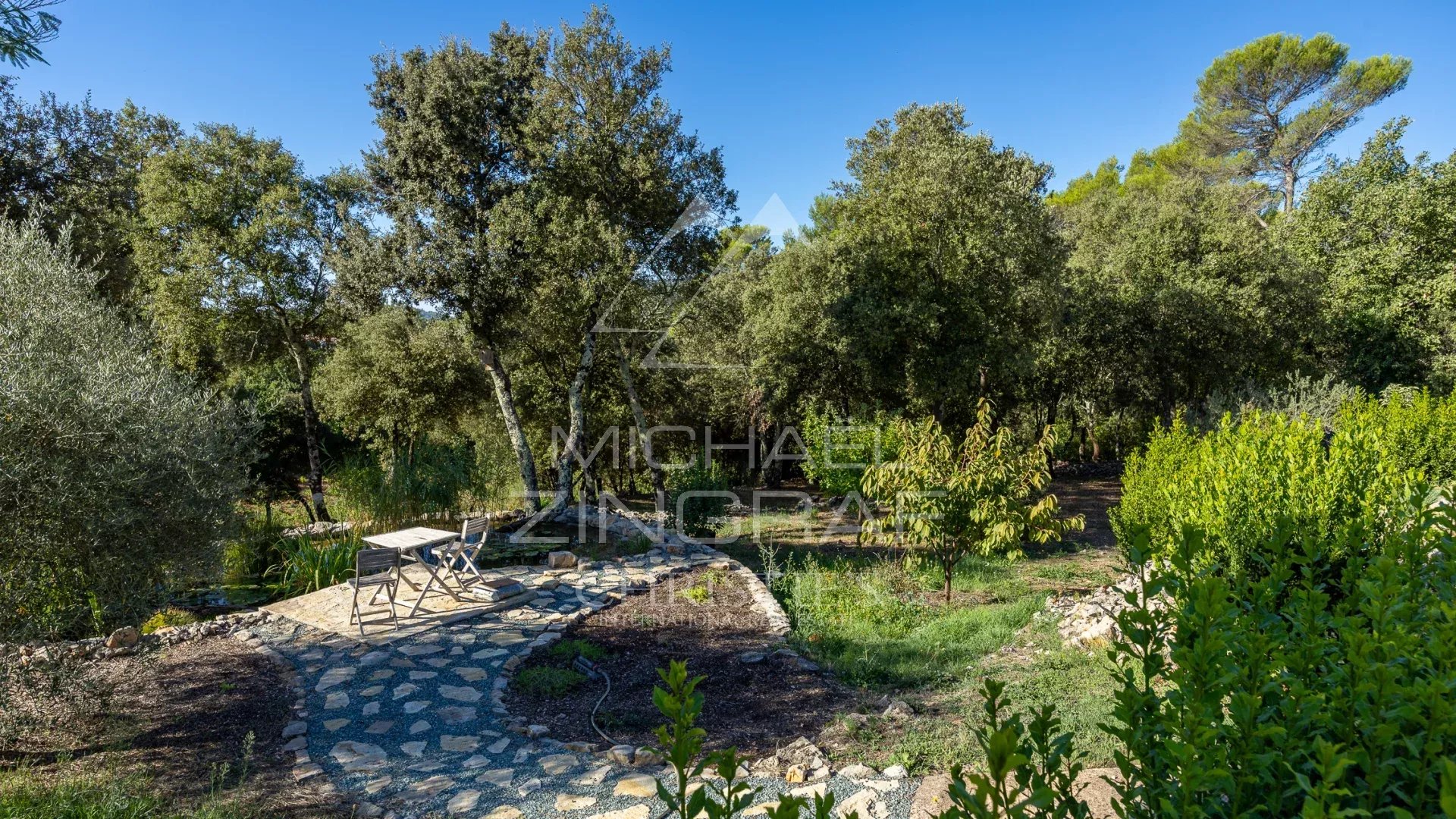 Jardin de propriété en Provence Jardin d'une propriété en Provence avec des arbres et une table en pierre.
