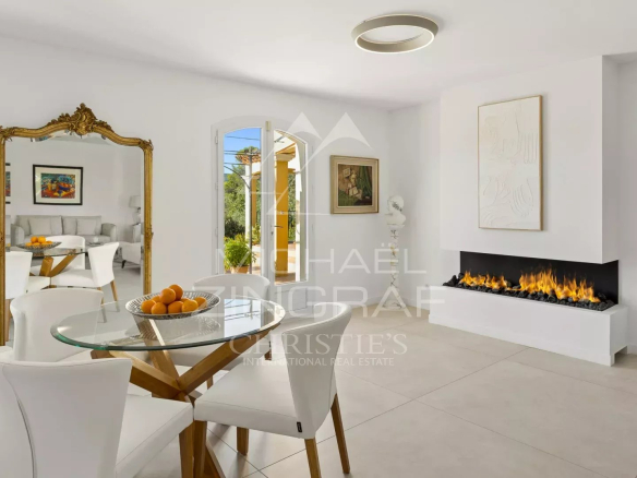 Intérieur d'une bastide moderne avec un salon lumineux, une table à manger et une cheminée.