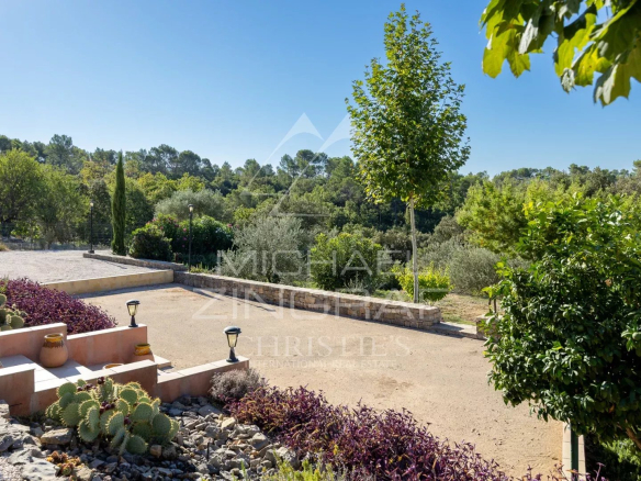Vue d'un jardin avec des plantes méditerranéennes et des arbres, dans un environnement paisible.