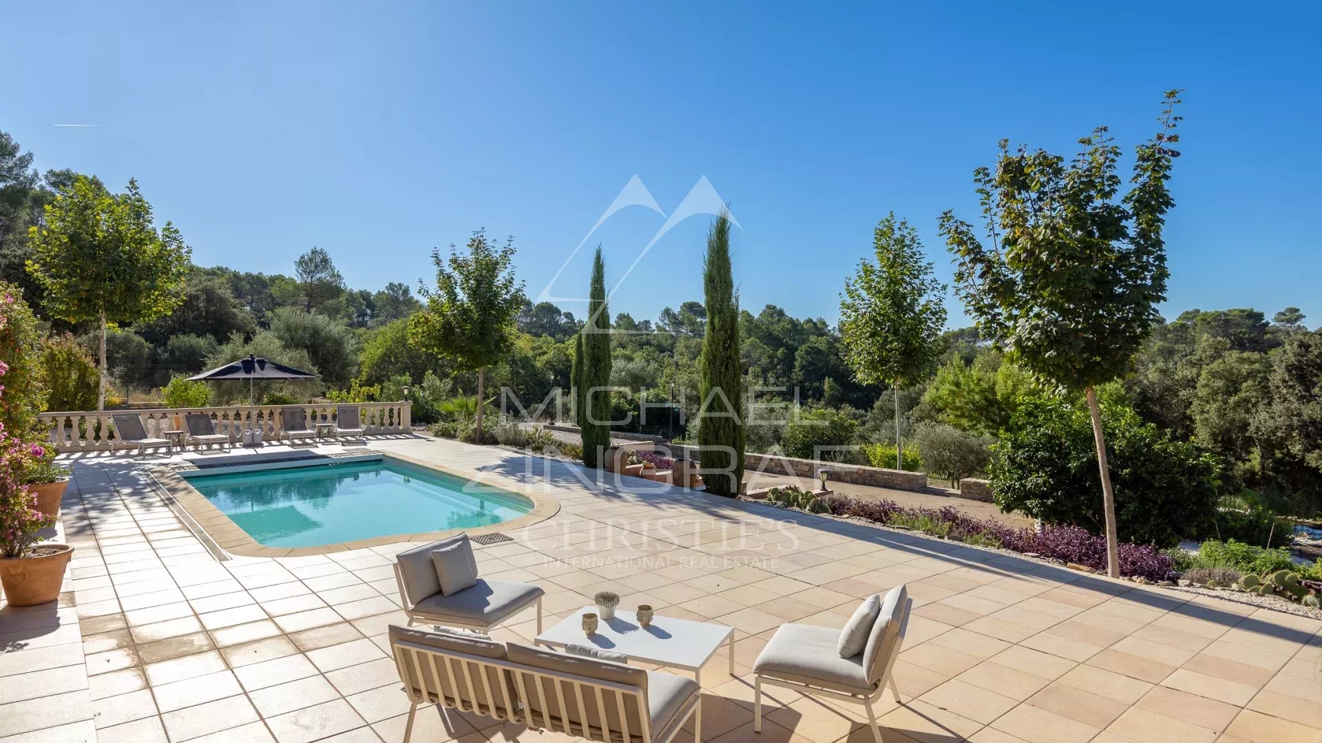 Propriété en Provence avec piscine Terrasse ensoleillée avec piscine, chaises et vue sur la nature en Provence.