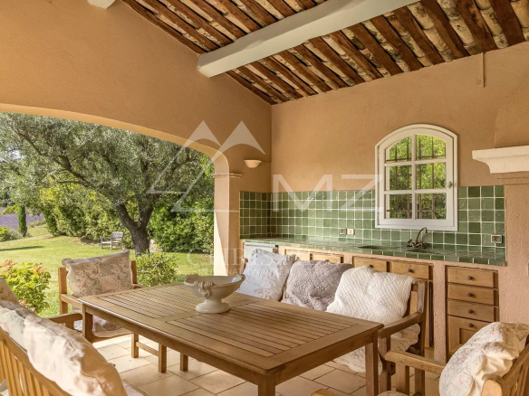 Terrasse d'une propriété à Saint-Vallier-de-Thiey avec mobilier en bois et cuisine extérieure.