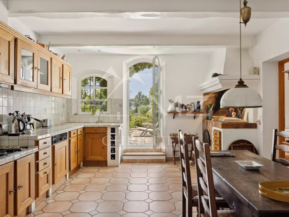 Cuisine chaleureuse avec cheminée et vue sur l'extérieur dans une propriété à Saint-Vallier-de-Thiey.