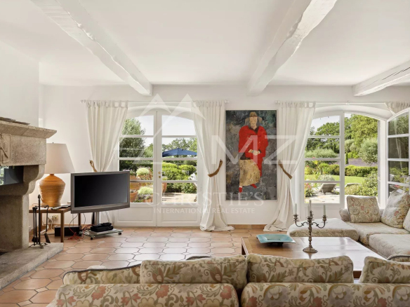 Intérieur d'une propriété avec salon lumineux, cheminée et vue sur le jardin.